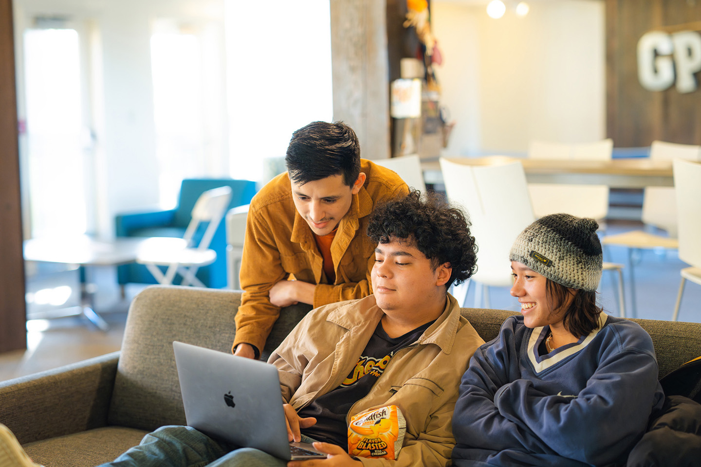 Three friends group together to work on a single laptop.