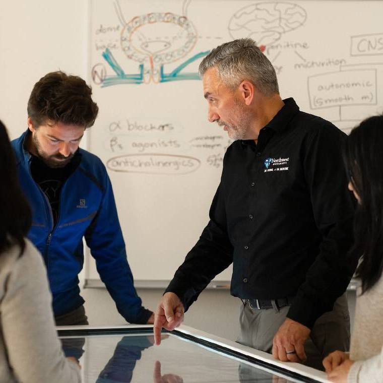 Students study an Anatomage table with their professor.