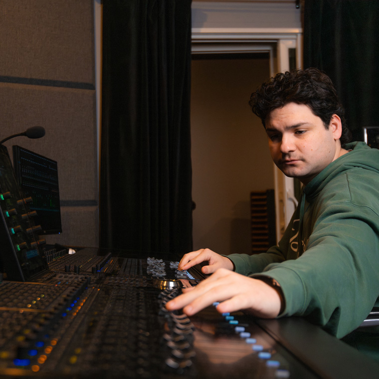 Student adjusting sliders on a sound board in the Creatio Studios at Northwest University