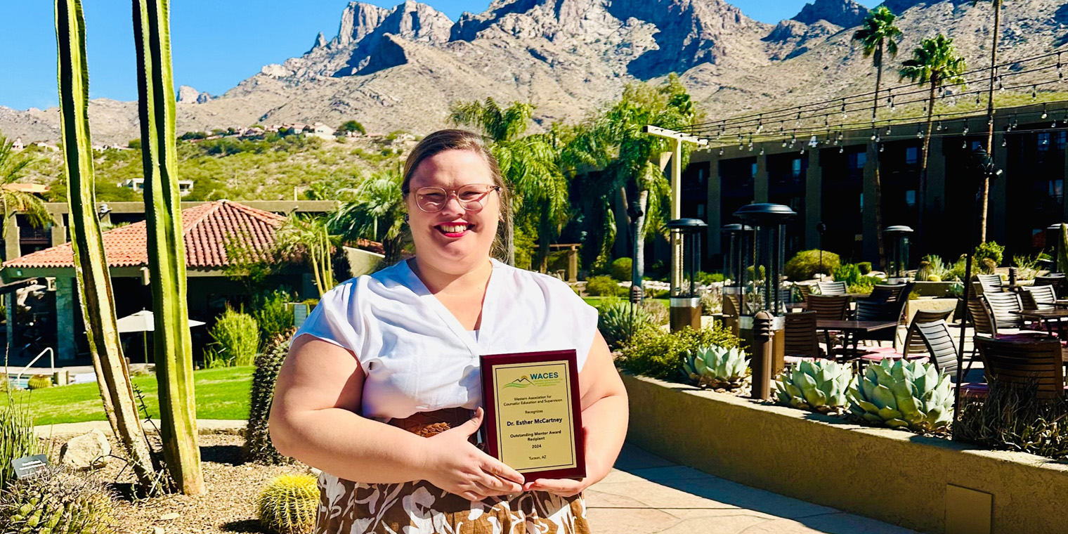 Esther McCartney holding a plaque in the sunshine